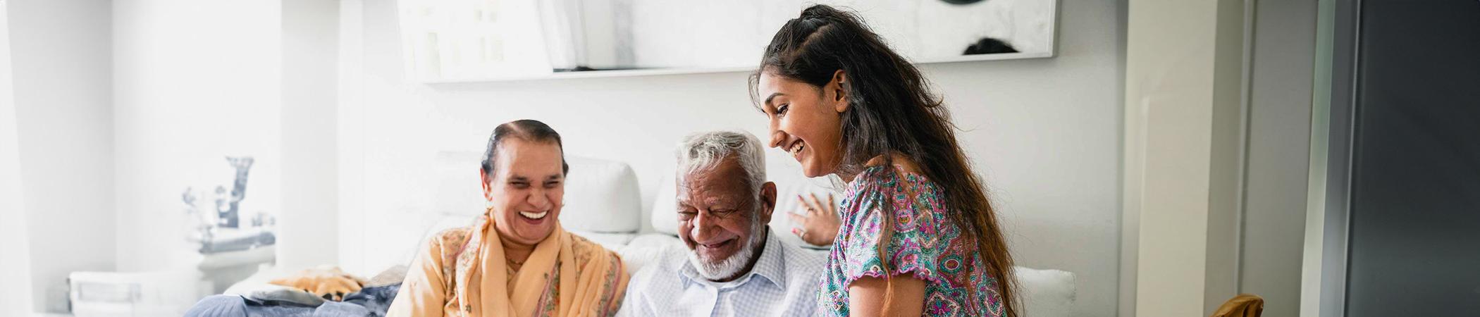 Young person smiling showing smiling older couple their mobile phone